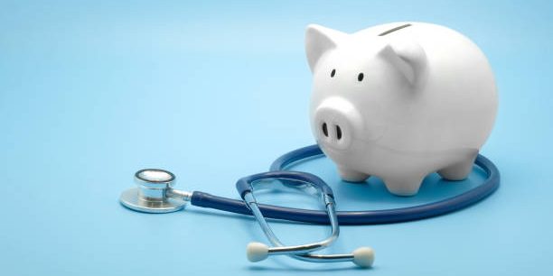 Piggy bank with stethoscope isolated on light blue background with copy space. Health care financial checkup or saving for medical insurance costs concept.